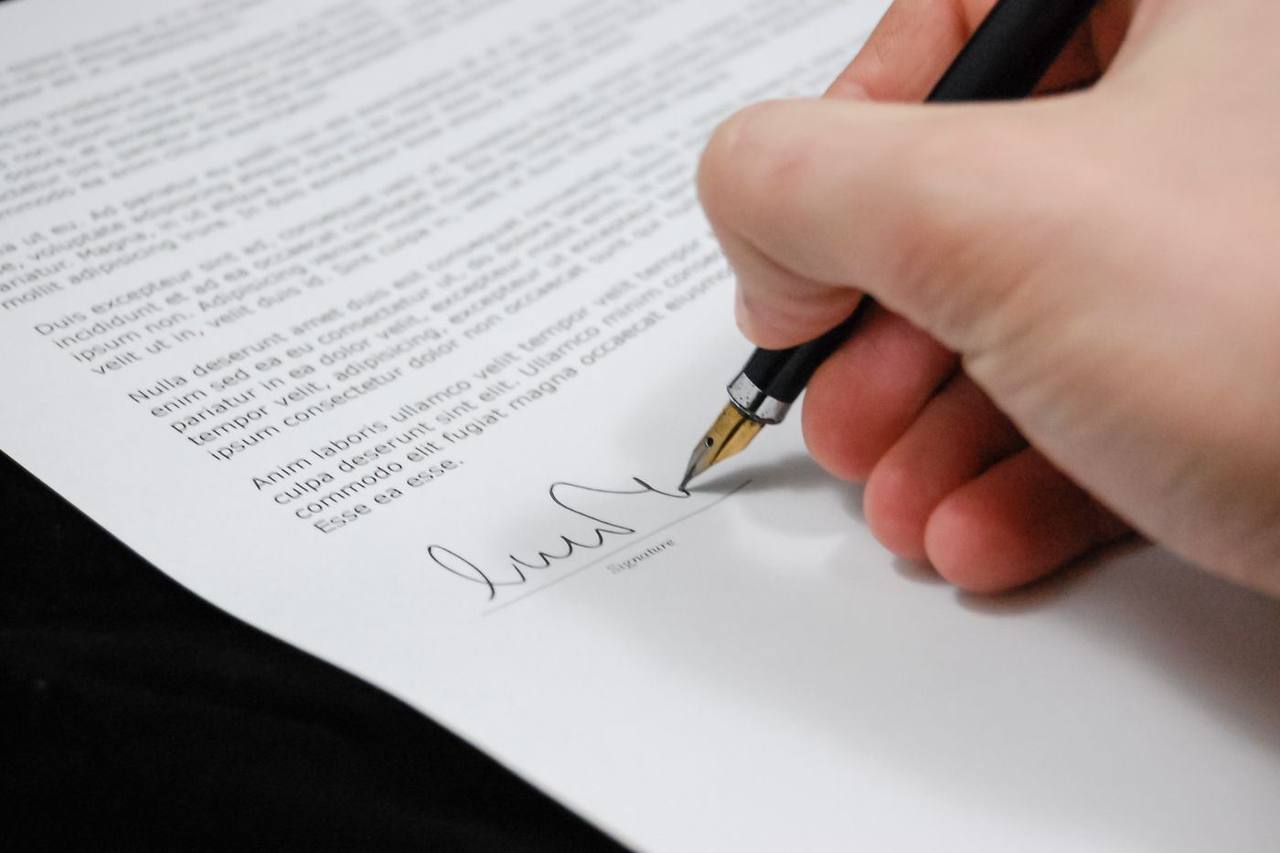 A hand signing a legal contract