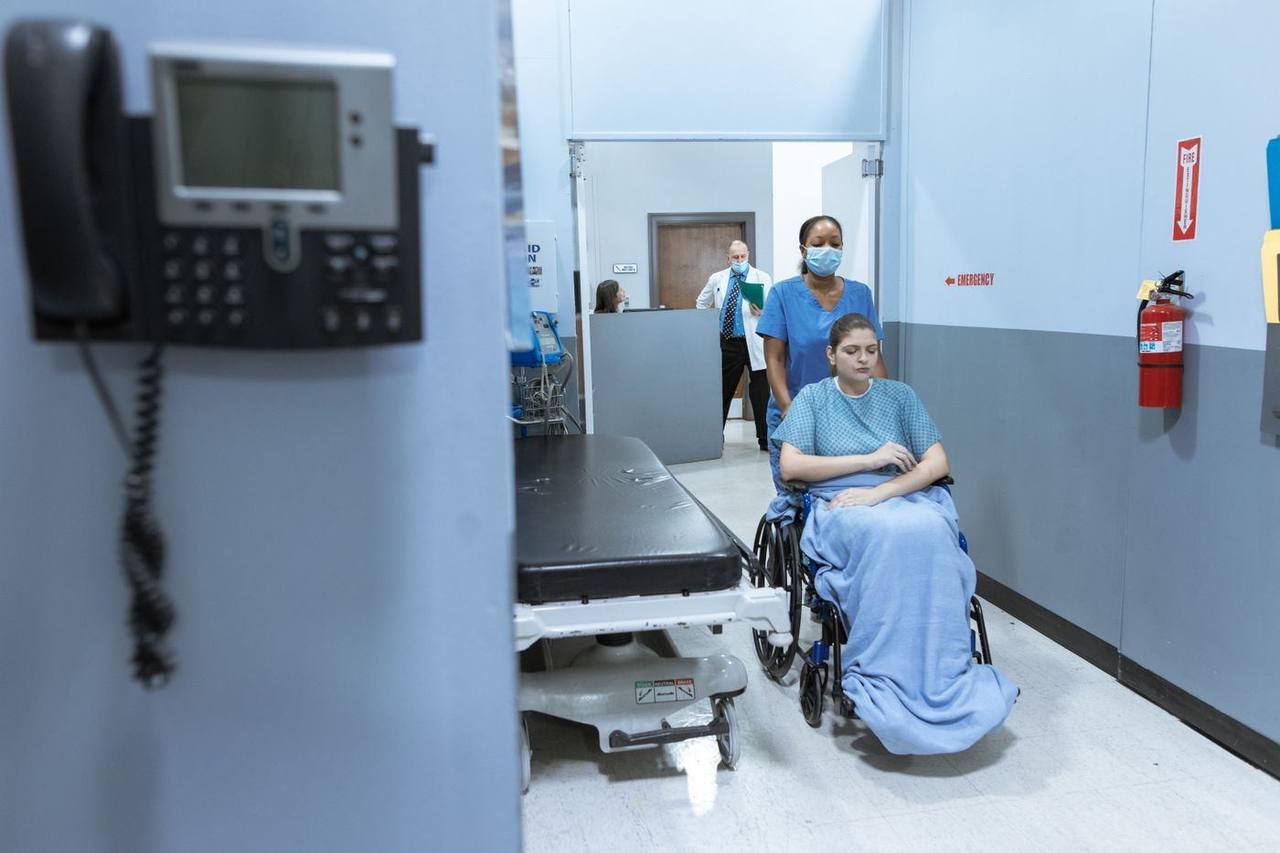 A nurse assisting a patient in a hospital corridor